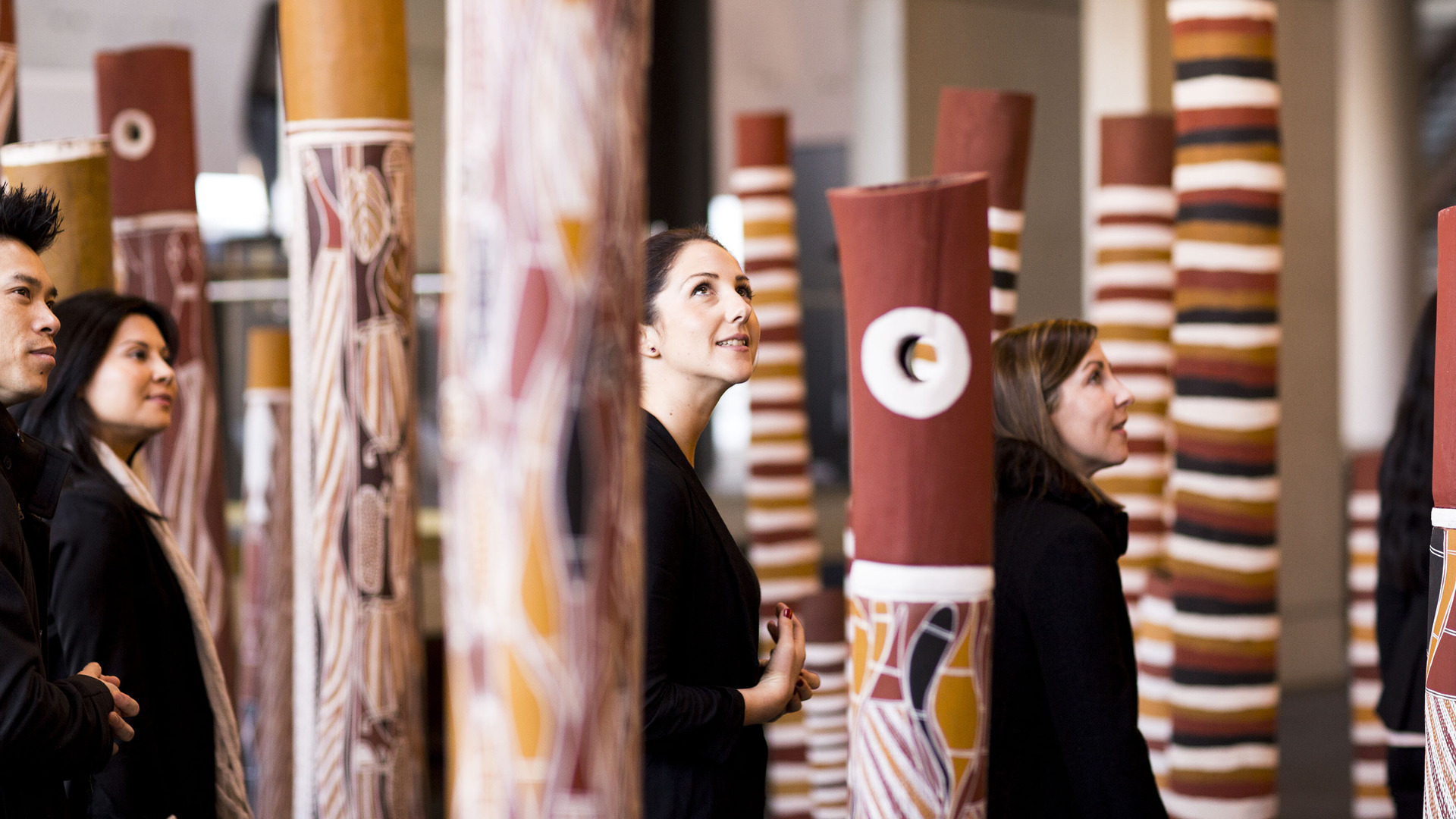 A group of people walk through an Aboriginal artwork.