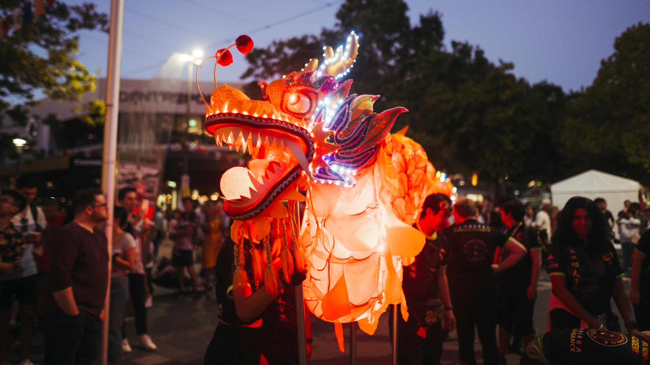 An illuminated dragon costume at a nighttime market.