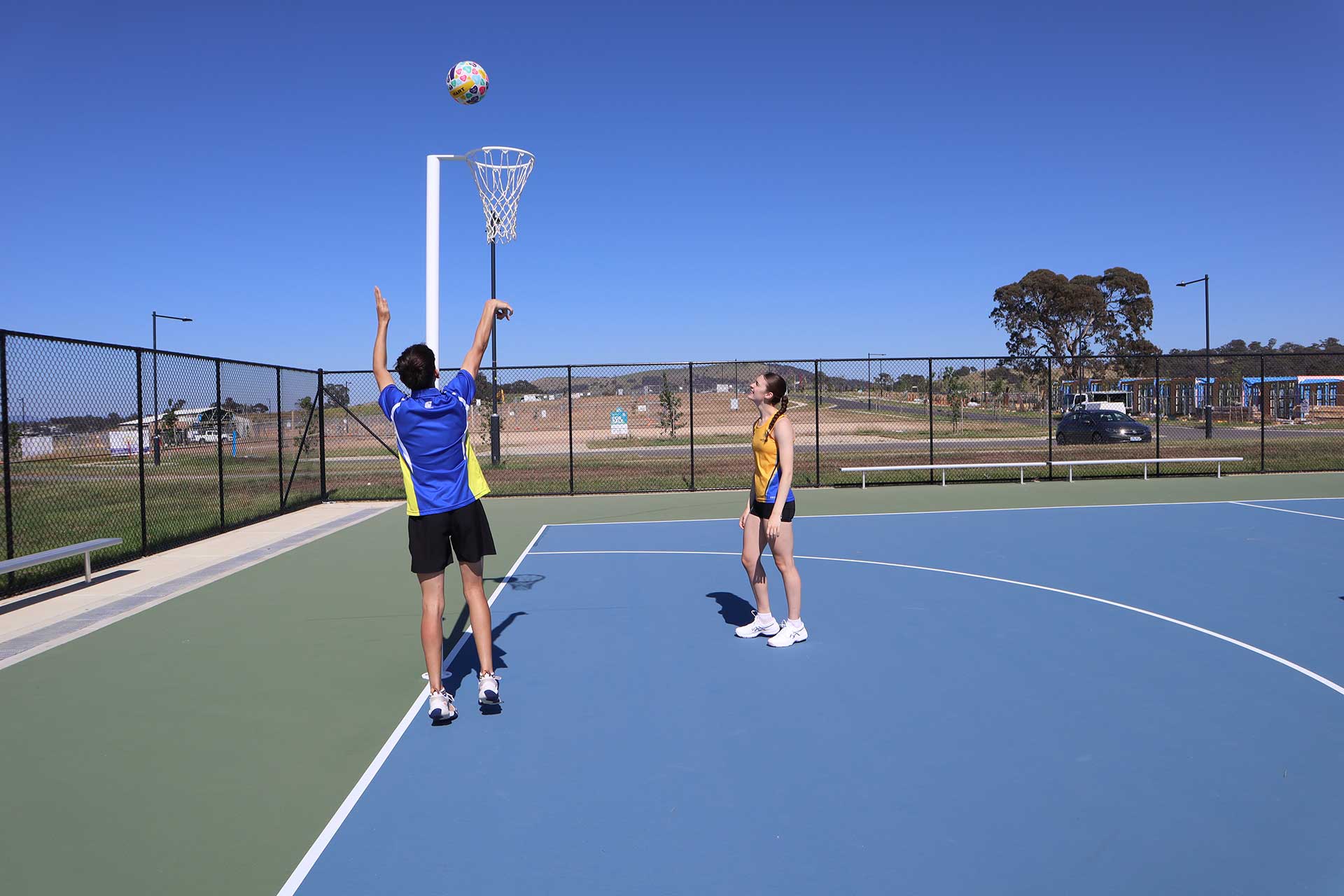 Two people play netball on a new court.