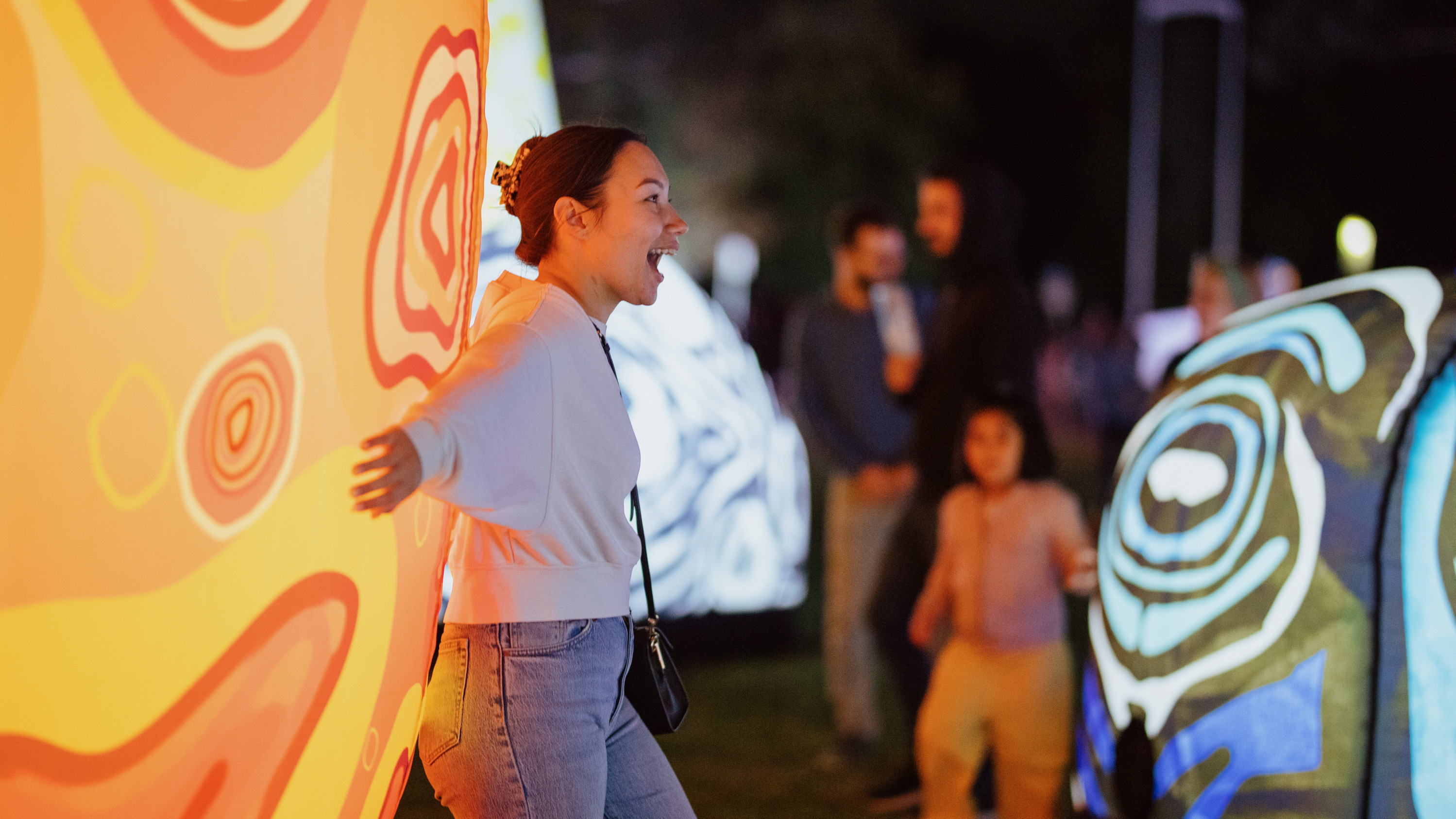 A woman stands next to an illuminated sculpture.