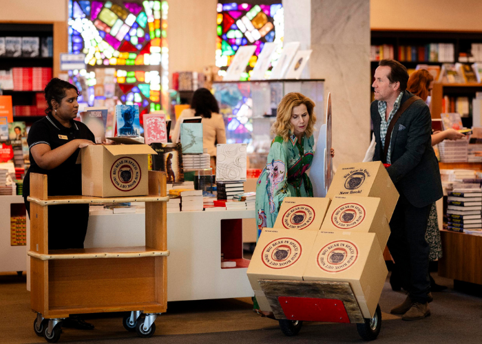 A man and a woman move boxes inside a bookstore. 