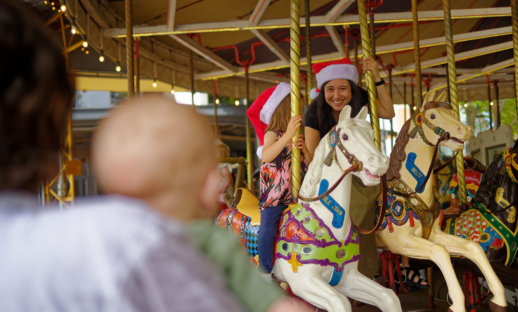 Mother and daughter smile as they ride the merry-go-round. 